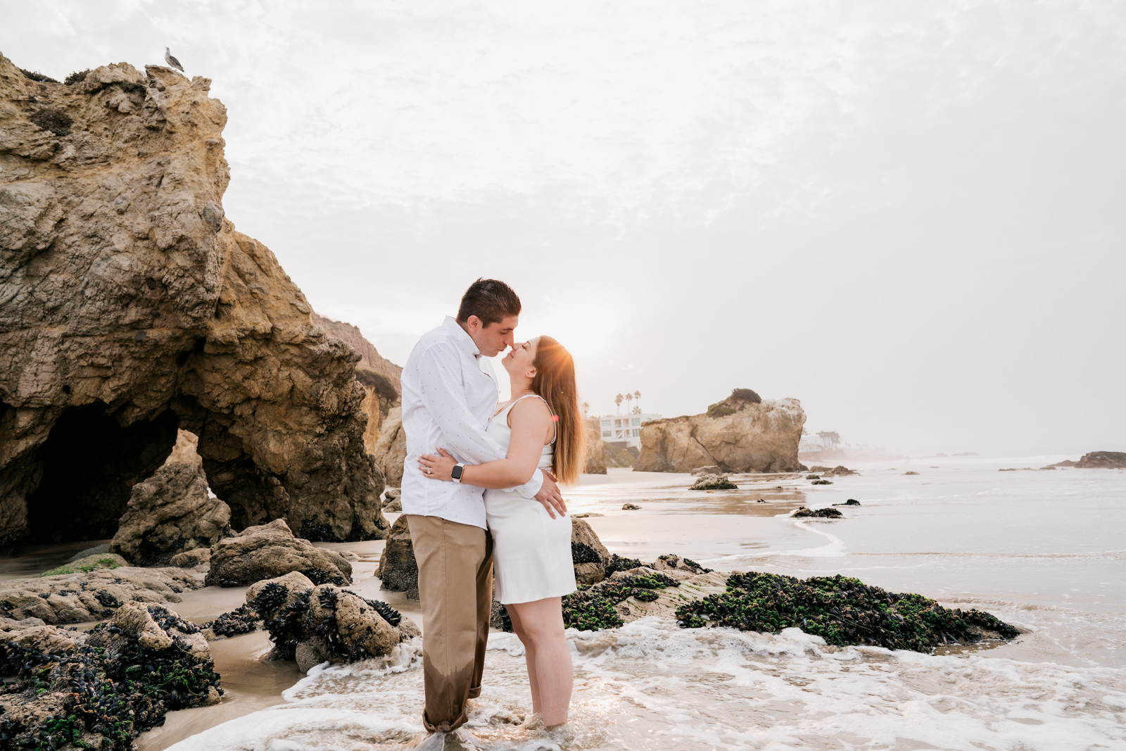 Couple embrace each other on beach infront of sunrise