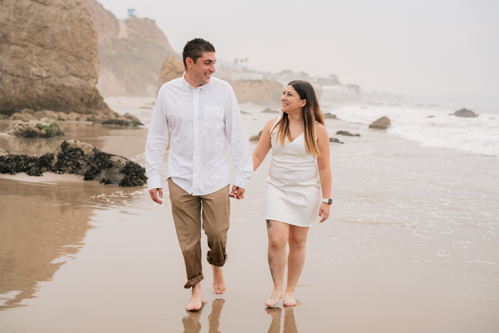 Couple holding hands walking on beach